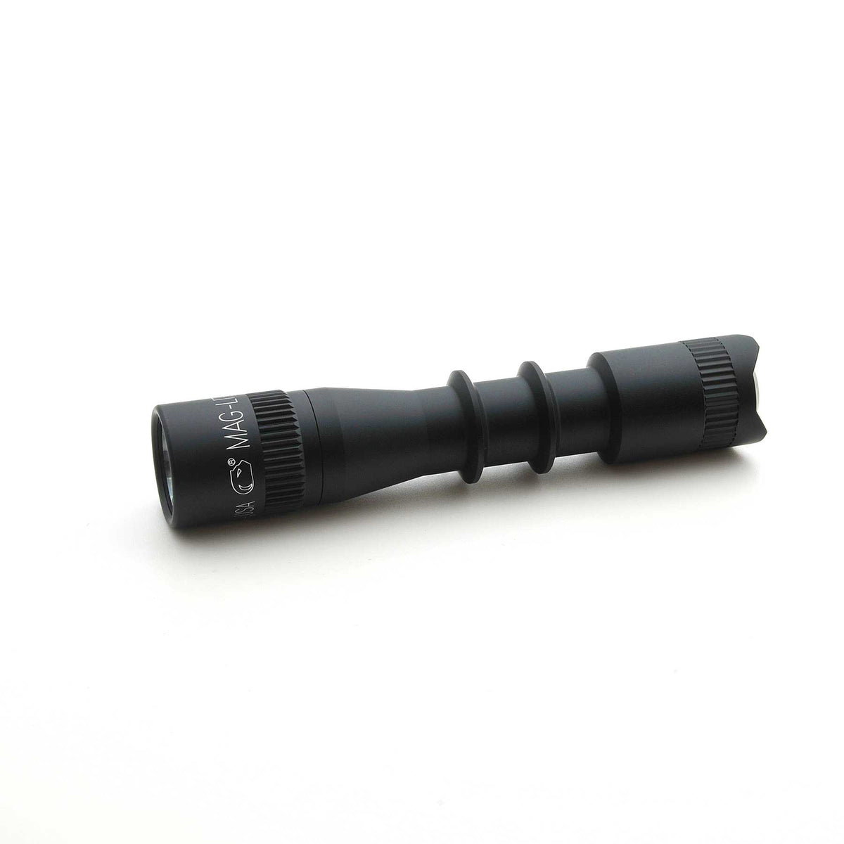 Diagonal bottom-right view of MAG-TAC 2 TL Black Plain Bezel flashlight highlighting the knurled grip and tail end