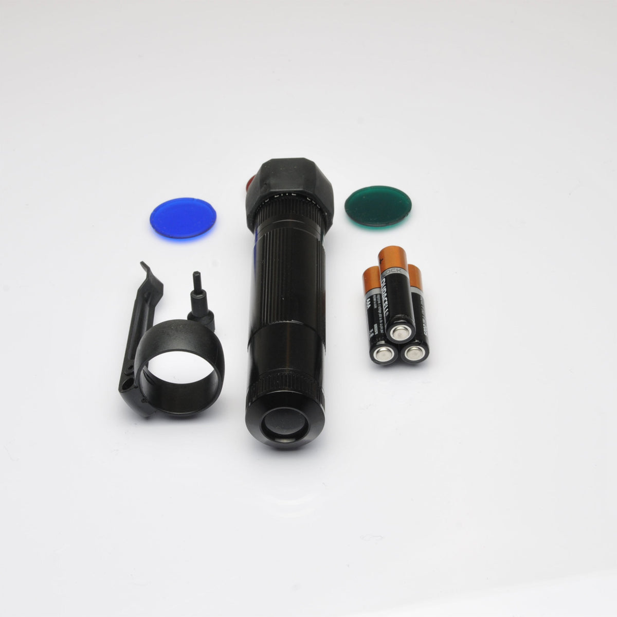 Close up of black flashlight with a blue disc nearby on a white surface