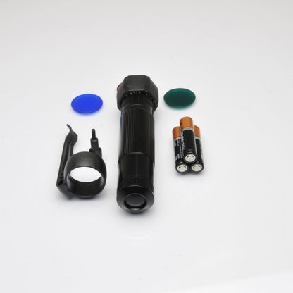 Close up of black flashlight with a blue disc nearby on a white surface