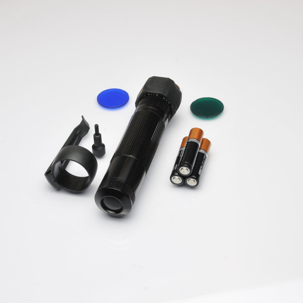Black flashlight with orange batteries and a green disc on a white surface