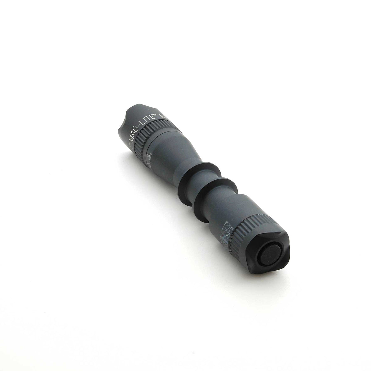 Close-up of MAG-TAC 2 TM black crown bezel on a flashlight