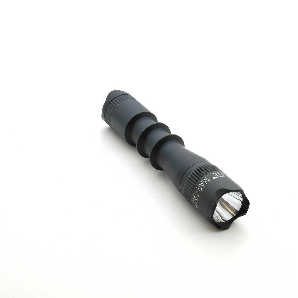 Black MAG-TAC 2 TM flashlight with crown bezel and knurled grip on white background.