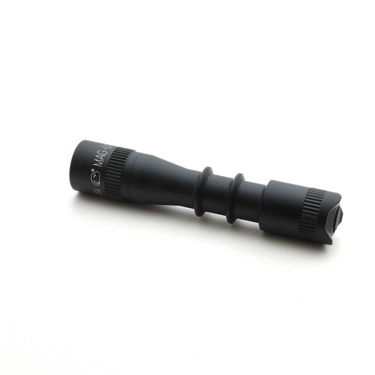 Black MAG-TAC 2 TL flashlight with plain bezel resting on a white surface.
