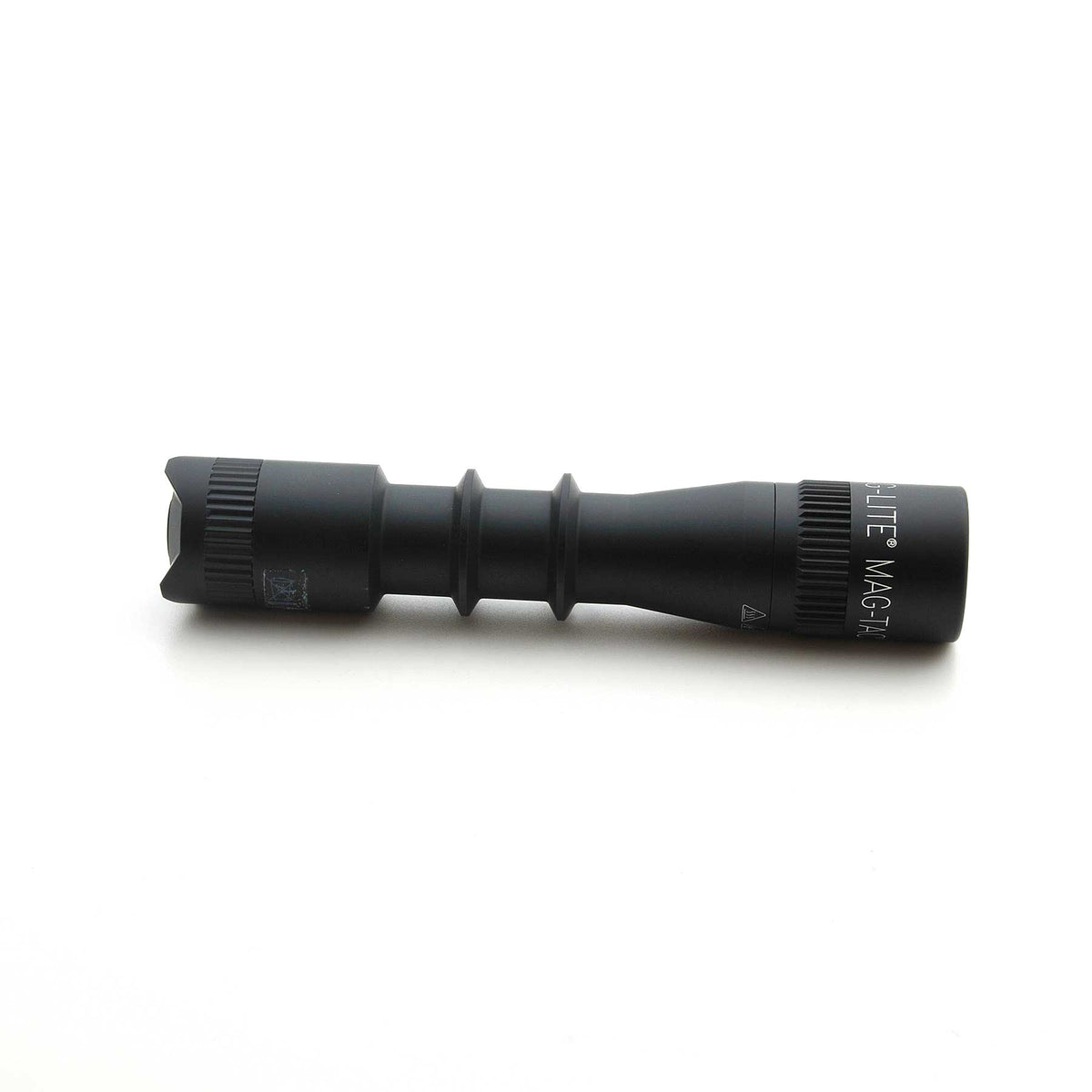 Partial view of MAG-TAC 2 TL black plain bezel flashlight on white background showing the textured midsection.