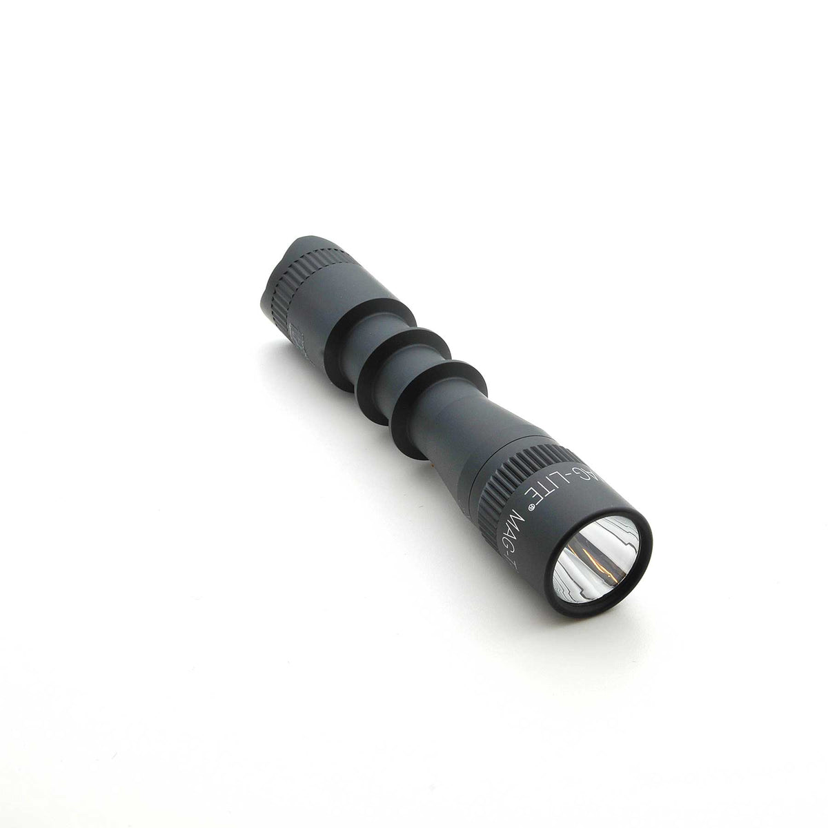 Close up of MAG-TAC 2 TL black tactical flashlight head with knurled bezel and matte finish.