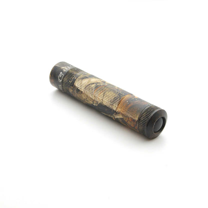 Maglite XL50 flashlight in Mossy Oak New Country DNA camouflage lying diagonally on a white surface