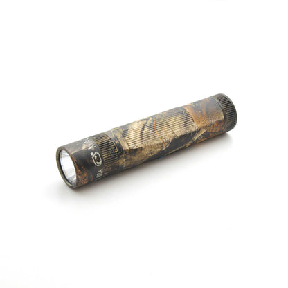 Maglite XL50 flashlight in Mossy Oak New Country DNA camouflage with knurled grip shown diagonally on a white background