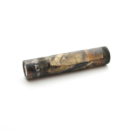 Mossy Oak New Country DNA camouflage Maglite XL50 flashlight with end cap visible against a white backdrop