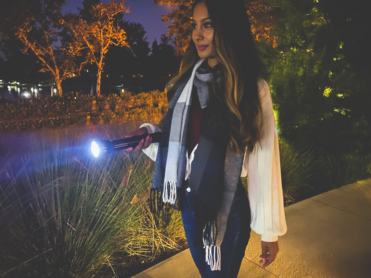 Woman outdoors at night holding a black ML300L long running LED flashlight with a bright beam