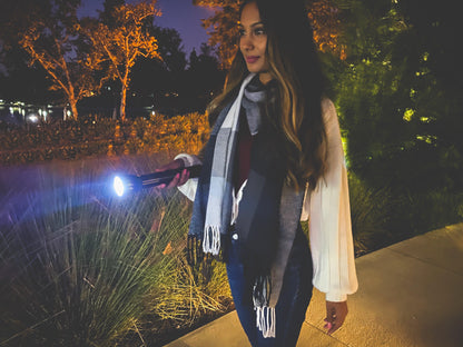 Woman outdoors at night holding a black ML300L long running LED flashlight with a bright beam