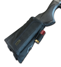 Partial close up of a shotgun butt stock with a shell holder attached against a black background