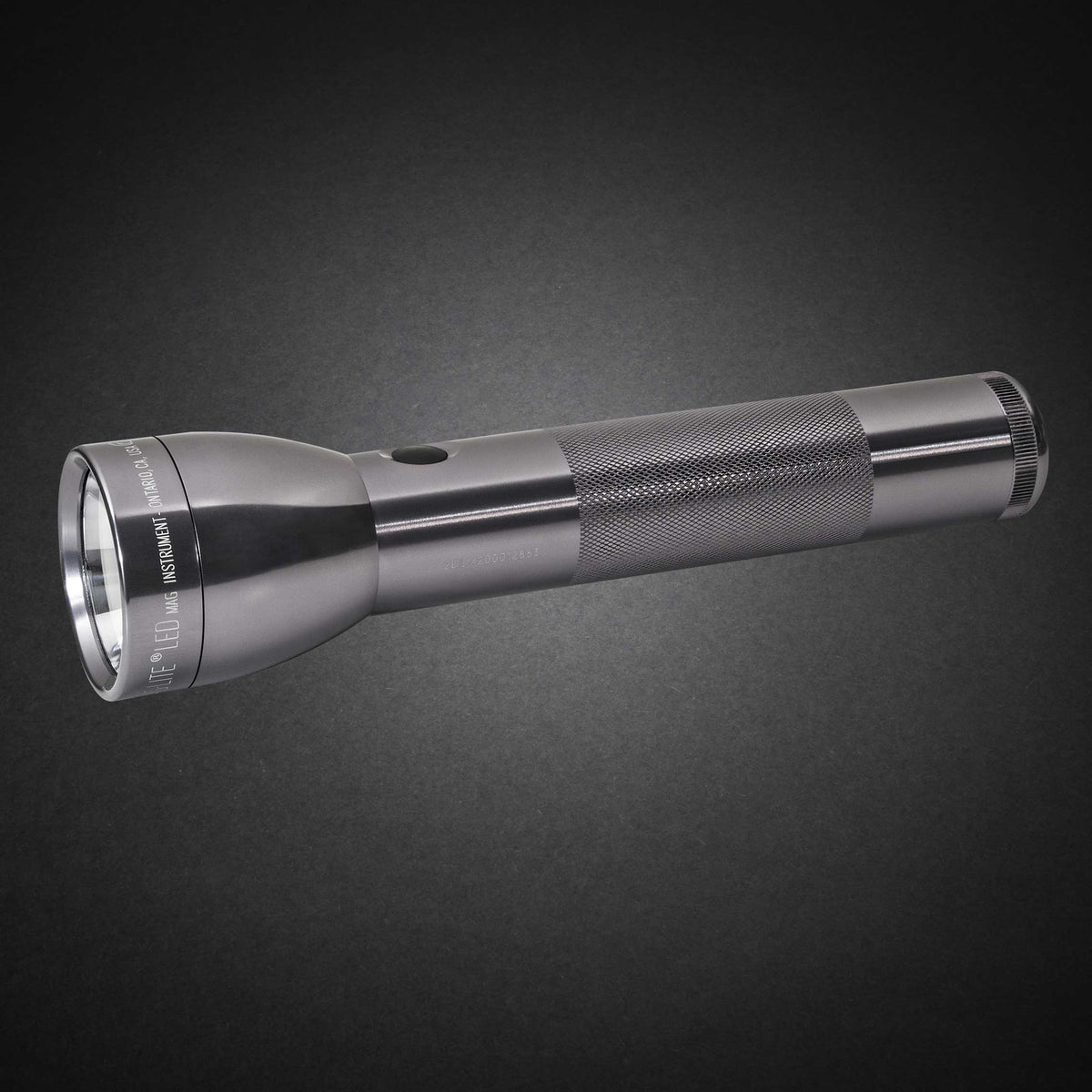 Gray ML300L LED 2-Cell D flashlight with knurled grip shown diagonally on a dark surface